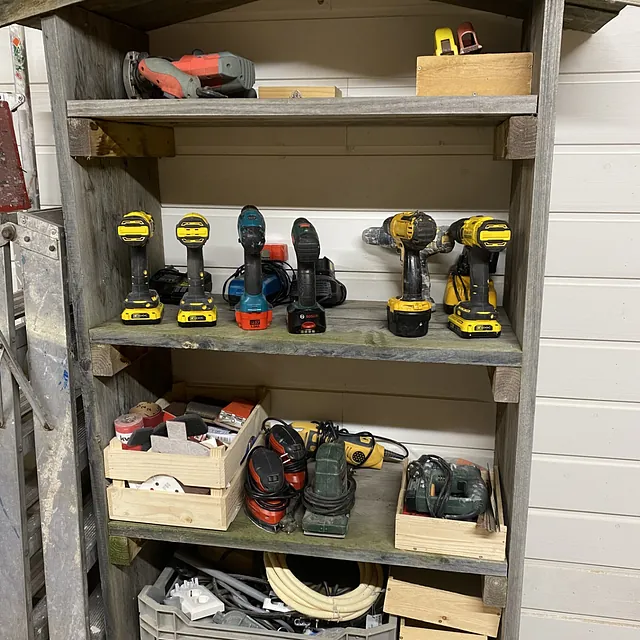 Houten stellingkast met accuboormachines en schuurmachines in de klushut